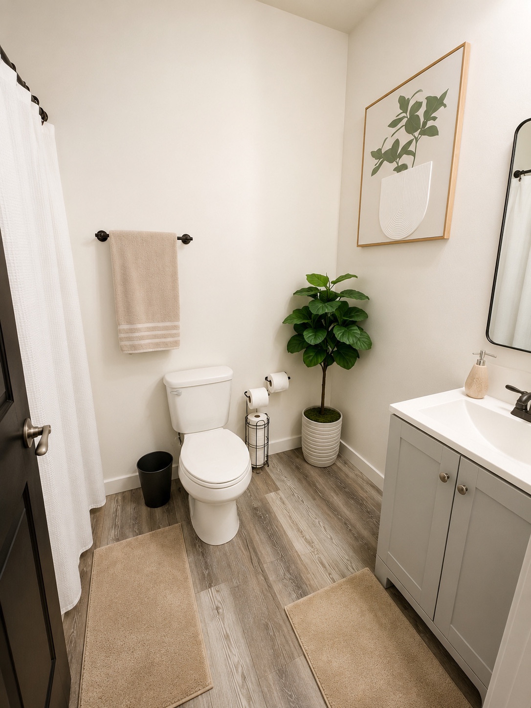 Clean full bathroom with a grey vanity, white countertop, black-framed mirror, and botanical art.